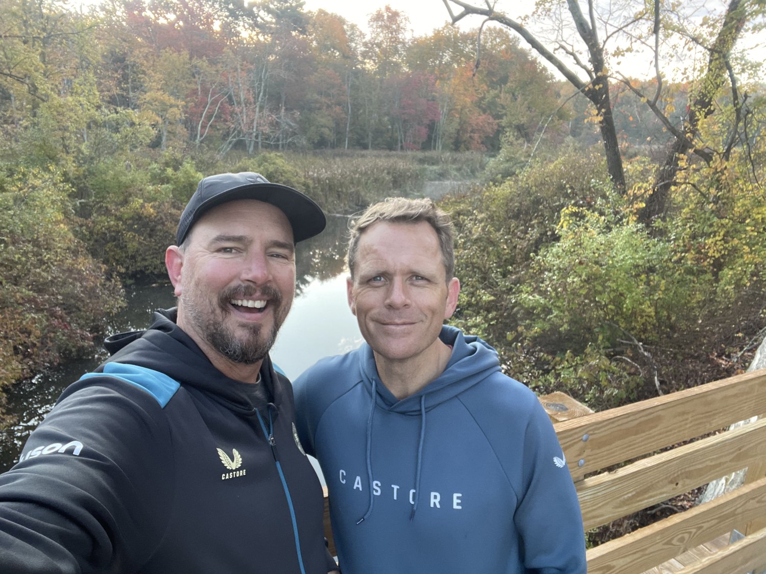 Al and Bilos smiling together beside a wooden bridge outdoors