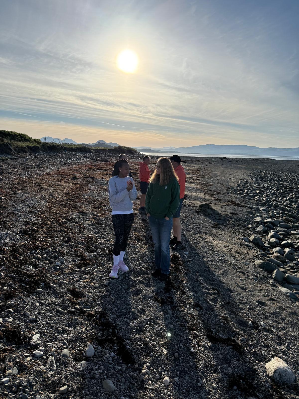 Retreat participants walking on the rocky shoreline in evening light